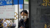 A resident waiting for a food delivery looks out from behind a gate blocking an entrance to a residential area under lockdown amid the coronavirus disease (COVID-19) pandemic, in Shanghai, China REUTERS/Aly Song