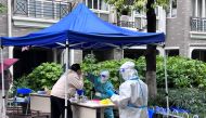 A medical worker in a protective suit collects a swab from a resident at a makeshift nucleic acid testing site inside a residential compound under lockdown in Shanghai, China April 14, 2022. Reuters/Xihao Jiang