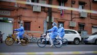 Workers in protective suits ride bicycles of bike-sharing service on a street during lockdown amid the coronavirus disease (COVID-19) pandemic, in Shanghai, China, April 15, 2022. REUTERS/Aly Song