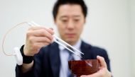 An employee of Kirin Holdings demonstrates chopsticks that can enhance food taste using an electrical stimulation waveform that was jointly developed by the company and Meiji University's School of Science and Technology Professor Homei Miyashita, in Tokyo, Japan April 15, 2022. REUTERS/Issei Kato