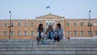 People sit at Syntagma square where the parliament building is seen in the background, in Athens, Greece April 20, 2022. REUTERS/Costas Baltas


