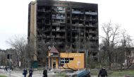 People walk past a residential building heavily damaged during Ukraine-Russia conflict in the southern port city of Mariupol, Ukraine April 21, 2022. REUTERS/Alexander Ermochenko

