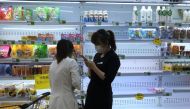 Customers shop in front of a half-empty freezer for diary products, following the coronavirus disease (COVID-19) outbreak, at a supermarket in Beijing, China April 25, 2022. REUTERS/Tingshu Wang