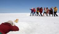 A boy takes photos of tourists behind a toy dinosaur for a fee, at the Uyuni Salt Flat in Bolivia March 27, 2022. Picture taken March 27, 2022. REUTERS/Claudia Morales