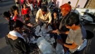 A man breaks a block of ice to distribute it among the residents of a slum during hot weather in Ahmedabad, India, April 28, 2022. REUTERS/Amit Dave


