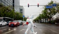 A worker wearing a protective suit and carrying disinfection equipment crosses a road amid the coronavirus disease (COVID-19) outbreak in Beijing, China April 27, 2022. REUTERS/Carlos Garcia Rawlins/File Photo