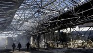 People walk at a damaged area inside a burning plant, following Russian shelling amid Russia's attack on Ukraine, in Kharkiv, Ukraine, April 30, 2022. REUTERS/Ricardo Moraes


