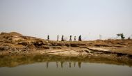 Women and children carry containers after filling them with water at an abandoned stone quarry on a hot day in Chipiya Abhaypur village in the northern state of Uttar Pradesh, India, May 4, 2022. Reuters/Ritesh Shukla