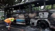 A man looks at a damaged bus of Sri Lanka's ruling party supporters after it was set on fire during a clash of pro and anti-government demonstrators near the Prime Minister's official residence, amid the country's economic crisis, in Colombo, Sri Lanka, May 10, 2022. REUTERS