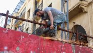 A worker uses a saw during the works to remove a concrete barrier blocking a street leading to the Parliament building, in Beirut, Lebanon May 23, 2022. REUTERS