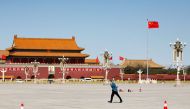 A man braving the wind walks past the Chinese flag on the Tiananmen Square, before the opening session of the Chinese People's Political Consultative Conference (CPPCC) in Beijing, China March 4, 2022. REUTERS/Carlos Garcia Rawlins