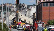 Firefighters and rescue workers stand at the site of a collapsed Morandi Bridge in the port city of Genoa, Italy August 15, 2018. REUTERS/Stefano Rellandini


