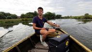 A postman of French postal service company La Poste distributes letters and parcels from a boat to residents who live in Salpwerick around the Marais Audomarois, France, July 28, 2022.  REUTERS/Pascal Rossignol