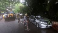 People walk past a damaged car after a wall of a residential society collapsed on it amidst heavy rainfall in Mumbai, India, July 5, 2022. REUTERS/Francis Mascarenhas/File Photo