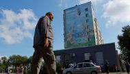 A local resident walks in front a mural painted on the wall of an apartment building in the Russian-controlled city of Enerhodar in the Zaporizhzhia region, Ukraine on August 4, 2022. (Reuters/Alexander Ermochenko)