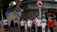 People wear face masks as they stand in a street following a coronavirus disease (COVID-19) outbreak, in Beijing, China, August 3, 2022. Reuters/Thomas Peter/File Photo