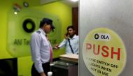 An employee speaks over his phone as a private security guard looks on at the front desk inside the office of Ola cab service in Gurugram, April 20, 2016. Reuters/Anindito Mukherjee/File Photo
