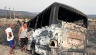 Men inspect a bus that was burnt following a wildfire in El Kala, in Al Tarf province, Algeria August 18, 2022. REUTERS/Ramzi Boudina