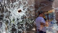 A woman stands behind a broken window of the hotel Central, which was damaged by recent shelling in the course of Ukraine-Russia conflict in Donetsk, Ukraine, August 23, 2022. (REUTERS/Alexander Ermochenko)