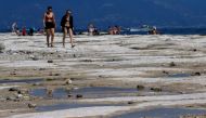 People walk as underwater rocks emerge from the water of Lake Garda after northern Italy experienced the worst drought in 70 years in Sirmione, Italy, on August 16, 2022. File Photo / Reuters
