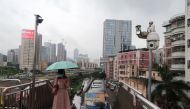A woman holding an umbrella walks on a pedestrian bridge by surveillance cameras, near Caopu in Shenzhen's Luohu district, Guangdong province, China July 5, 2022. REUTERS/David Kirton

