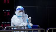 A medical worker in a protective suit uses a fan at a nucleic acid testing station, following the coronavirus disease (COVID-19) outbreak, amid a heatwave warning in Shanghai, China, on August 23, 2022. REUTERS/Aly Song
