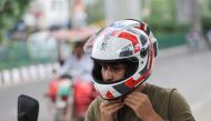 An employee of Shellios Technolabs, that manufactures motorcycle helmet claimed to be fitted with filters and a fan at the back of the helmet, puts on the helmet, near their assembling factory unit in an industrial area, in New Delhi, India, August 23, 2022. REUTERS/Anushree Fadnavis