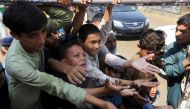 Boys, victims of the flood, reach out for food from a relief worker, following rains and floods during the monsoon season in Nowshera, Pakistan, August 30, 2022. (REUTERS/Fayaz Aziz)