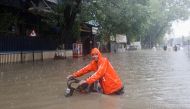 A man wades through a flooded street with his bike amidst heavy rainfall in Mumbai, India, July 5, 2022. (REUTERS/Francis Mascarenhas)