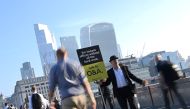 Workers pass by a sales person as they walk towards the City of London financial district, during the morning rush hour in London, Britain, September 8, 2021. REUTERS/Toby Melville/File Photo