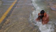 A displaced man cools off to avoid heat on flooded highway, following rains and floods during the monsoon season in Sehwan, Pakistan, on September 16, 2022. REUTERS/Akhtar Soomro 
