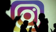 Silhouettes of mobile users are seen next to a screen projection of the Instagram logo in this picture illustration taken on March 28, 2018. File Photo / Reuters
