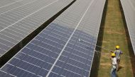 Workers clean photovoltaic panels inside a solar power plant in Gujarat, India, on July 2, 2015.  File Photo / Reuters