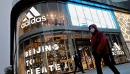 People walk past an Adidas store in a shopping district following an outbreak of the coronavirus disease (COVID-19) in Beijing, China, April 5, 2021. (REUTERS/Thomas Peter)