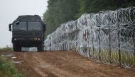  A view of a vehicle next to a fence built by Polish soldiers on the border between Poland and Belarus near the village of Nomiki, Poland, on August 26, 2021.   File Photo / Reuters
