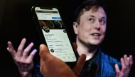 In this file photo taken on April 14, 2022 a phone screen displays the Twitter account of Elon Musk with a photo of him shown in the background, in Washington, DC. (Photo by Olivier Douliery / AFP)