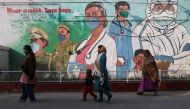 Women walk past a graffiti amidst the spread of the coronavirus disease (COVID-19) in New Delhi, India, February 7, 2022. REUTERS/Anushree Fadnavis
