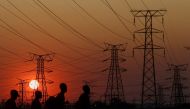 Locals walk past electricity pylons during frequent power outages from South African utility Eskom, caused by its ageing coal-fired plants, in Orlando, Soweto, South Africa, September 28, 2022. (REUTERS/Siphiwe Sibeko)