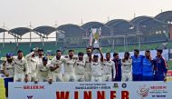 Team India pose as they hold the tournament trophy after winning on the fourth day of the second cricket Test match between Bangladesh and India. (Photo by Munir uz Zaman / AFP)