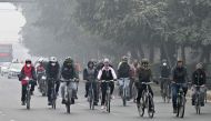 Cyclists take part in a pollution and smog awareness campaign as they ride along a street towards the Wagah border, in Lahore on December 25, 2022. (Photo by Arif ALI / AFP)