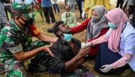 Health workers check a Rohingya refugee who was feeling sick after his arrival by boat in Krueng Raya, Indonesia's Aceh province on December 25, 2022. (Photo by Chaideer Mahyuddin / AFP)