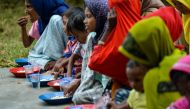 Rohingya refugees eat food in a temporary shelter following their arrival by boat in Laweueng, Aceh province on December 27, 2022. (Photo by Chaideer Mahyuddin / AFP)
