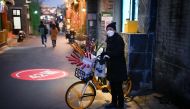 A snacks vendor waits for customers on a street in Beijing on January 2, 2023. (Photo by Wang Zhao / AFP)