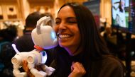 An attendee plays with the WowWee Dog-E, a robotic dog unique to every user, at ShowStoppers during the Consumer Electronics Show (CES) in Las Vegas, Nevada, on January 5, 2023. (Photo by Patrick T. Fallon / AFP)