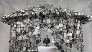 Indian artist Subodh Gupta poses in one of his installations, a hanging hut made with cooking pots collected from markets during his exhibition entitled 