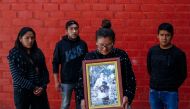 (Left to right) Milagros Samillan, Edson Samillan, Ysabel Samillan and Juan Samillan, sisters and brothers of Marco Antonio Samillan Sanga, a biologist by profession and doctor in training who died during the protests in Juliaca, pose for a photo holding an image of Marco Antonio at his home in Juliaca in southern Peru on January 14, 2023. (Photo by Juan Carlos CISNEROS / AFP)
