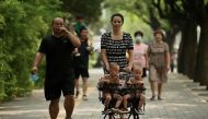 A woman pushes a trolley with twins along a street in Beijing on Aug. 2, 2022. (Photo: AFP)

