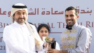 CEO of Qatar Media Corporation (QMC) H E Sheikh Abdulaziz bin Thani Al Thani hands trophy to Faleh Bughanaim, who rode Al Wakrah to win in HE Sheikh Joaan Bin Hamad Al Thani Trophy for Purebred Arabians at Al Rayyan Racecourse yesterday. 