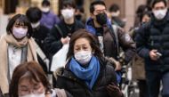 People wearing face masks cross a street in Tokyo on January 27, 2023. (Photo by Yuichi YAMAZAKI / AFP)
