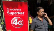 A man speaks on his mobile phone next to a Vodafone advertisement in Kolkata, India, September 26, 2016. REUTERS/Rupak De Chowdhuri
